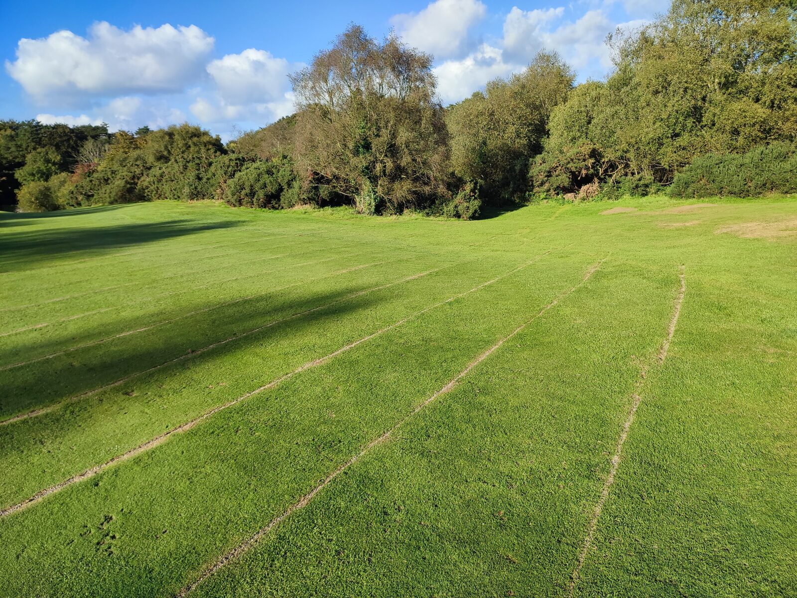 A fairway with faint parallel gravel-banding lines running across the turf